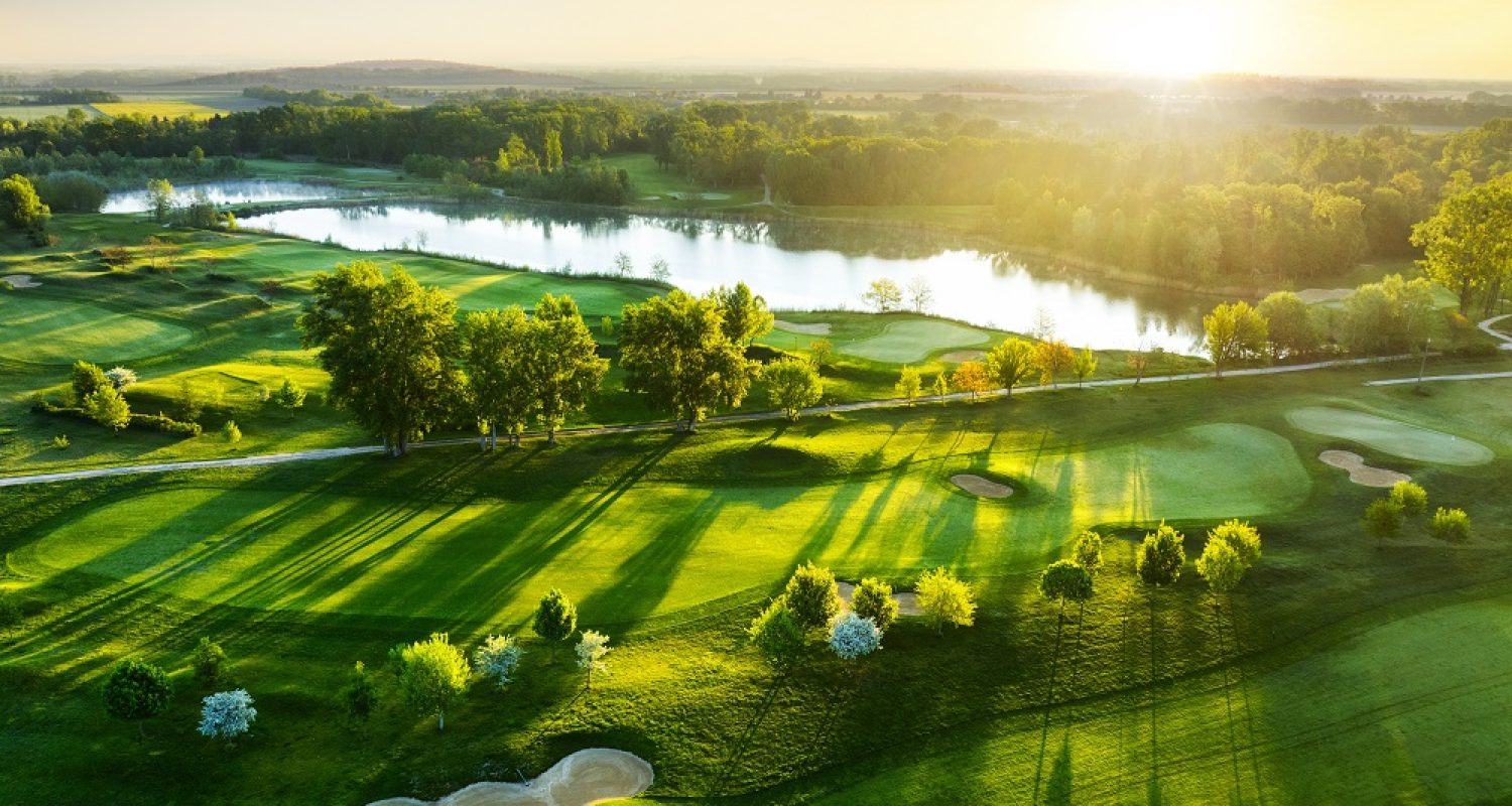 Aerial view of sunset over golf course with spring colored trees and lakes
